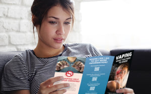 Pretty young-adult teen girl reading Vaping What You Need to Know pamphlet.